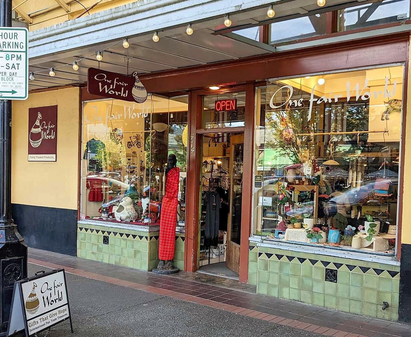 Outside view of One Fair World's Storefront at 474 Court St NE Salem, OR with wooden elder Maasai figure outside the door.